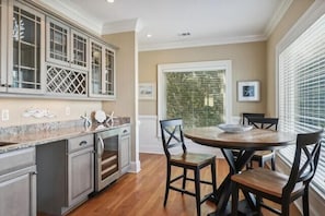 A kitchen with a round table and chairs, a window with blinds, and a door with a glass panel.