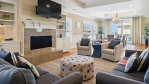 A living room with a fireplace, television, and seating area. - The Tip of Tybee Townhouse (Tybee Island)