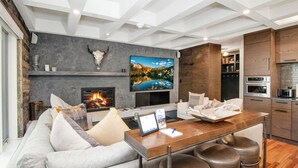 A modern living room with a fireplace, a television, and a bar area with stools. - Steps to Lionshead Gondola in Vail, TT4C (Vail)