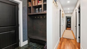 A hallway with a dark wooden door, a bookshelf, and a laundry area. - Steps to Lionshead Gondola in Vail, TT4C (Vail)