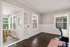 Spacious room with a large door, windows, and wainscoting, featuring a desk and chair.