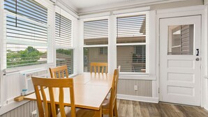 A dining area with a wooden table and chairs, large windows with blinds, and a white door. - Spacious housing for traveling professionals (Kansas City)