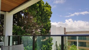 Ein Balkon mit Tisch und Stühlen, mit Blick auf ein Gebäude mit großen Fenstern und einer Rasenfläche.