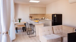 A modern kitchen with a central island, a dining area with a bench and chairs, and a living area with a sofa.