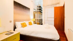 Ein modernes Hotelzimmer mit einem großen Bett, einem Holzkopfende, einem Nachttisch mit Lampe und Blick ins Freie.