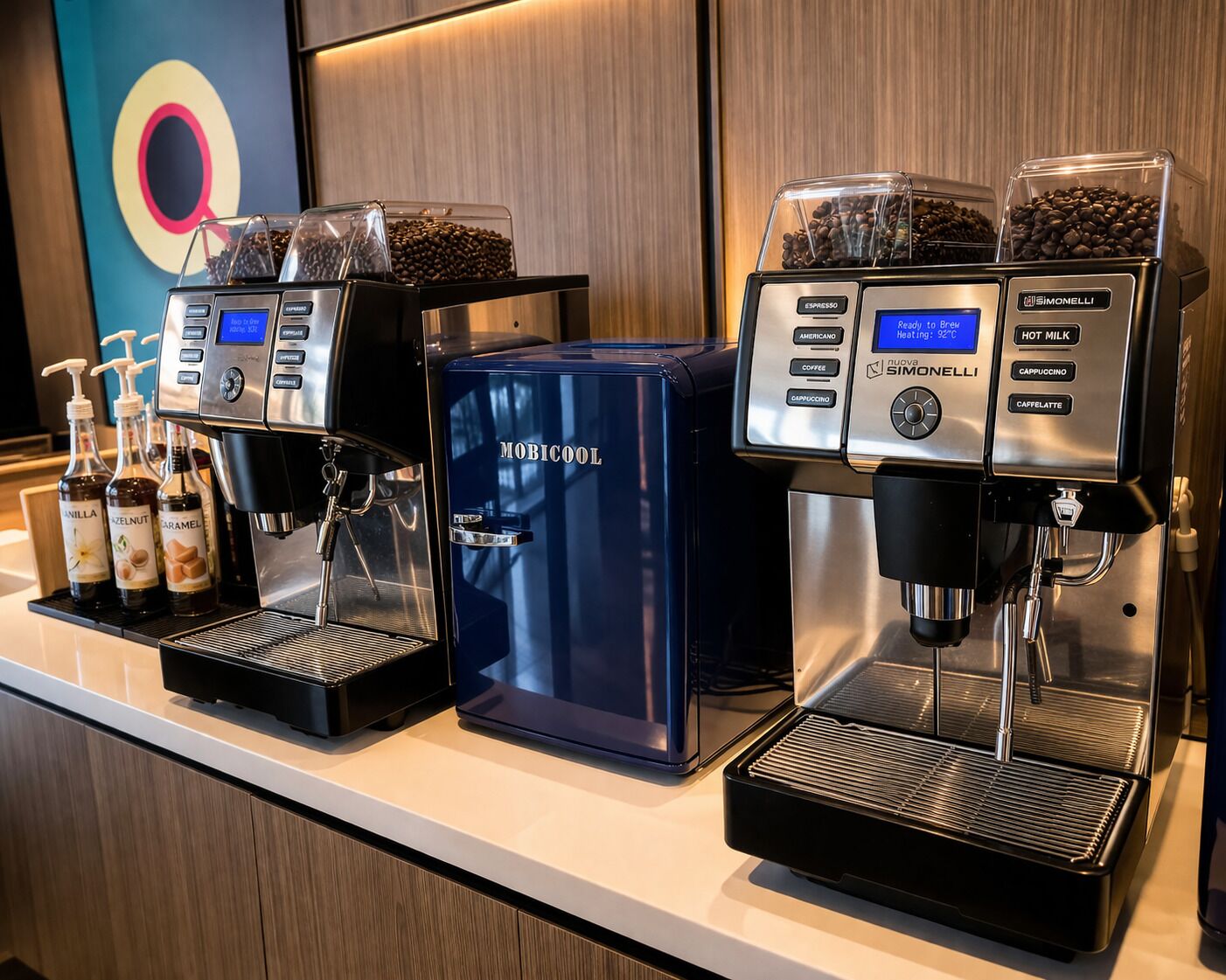 Two coffee machines, a blue espresso machine, and a Simonelli machine with coffee beans and milk options.
