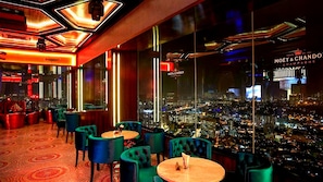 A modern bar with neon lights, green chairs, and a city view. - Sidemen Suites at Platinum KLCC (Kuala Lumpur)