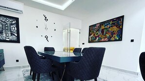 A modern dining area with a glass-top table, dark upholstered chairs, a patterned rug, and contemporary wall art. - Luxurious and cosy lodge in Dakar-Alamadies with private pool (Dakar)