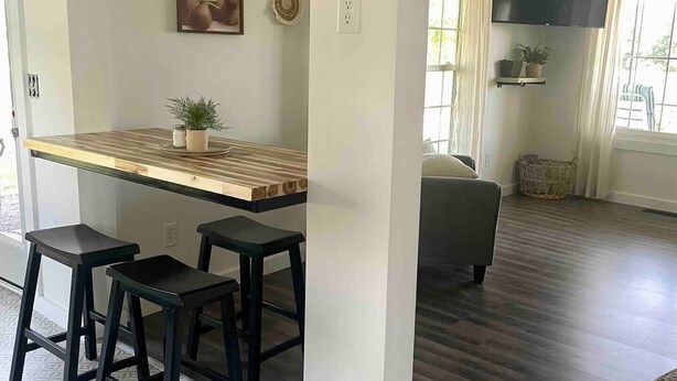 A modern kitchen with a wooden countertop, black stools, and a wall-mounted TV. - The Blue Door Place
 (Florence)