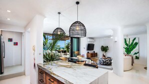 Een moderne keuken met een marmeren eiland, hanglampen en uitzicht op zee.