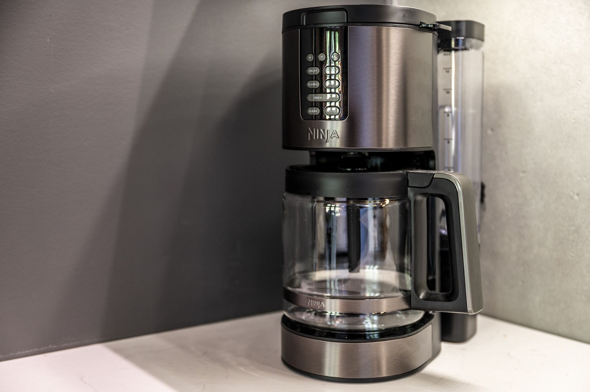 En kaffemaskine med digitalt display og en glaskande.