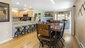 A spacious kitchen with wooden cabinets, a central island with stools, and a dining area with a wooden table and chairs. - 901 Crazy Horse Circle 2 Bedroom Condo by RedAwning (Edwards)