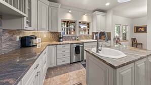 Une cuisine moderne avec des meubles blancs, des plans de travail en granit et un lave-vaisselle encastré.