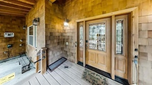 Une cabane en bois dotée d’un porche, d’un paillasson et d’une porte avec des panneaux de verre.
