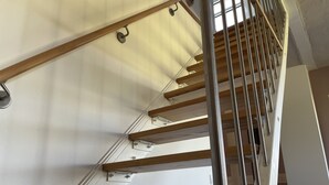 Una escalera de madera con barandales de metal y una pared blanca.