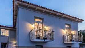 Un immeuble de deux étages doté d’un balcon au deuxième étage, agrémenté d’une balustrade et de plantes en pot.