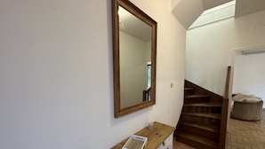 A hallway with a wooden bench, a mirror, and a staircase. - Maison Paisible, 15 min du Futuroscope & Arena (Fontaine-le-Comte)