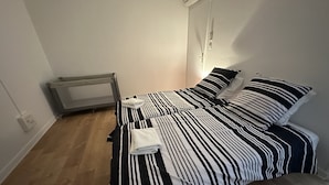 A room with two beds, a radiator, and a wall-mounted air conditioner. - Maison Paisible, 15 min du Futuroscope & Arena (Fontaine-le-Comte)