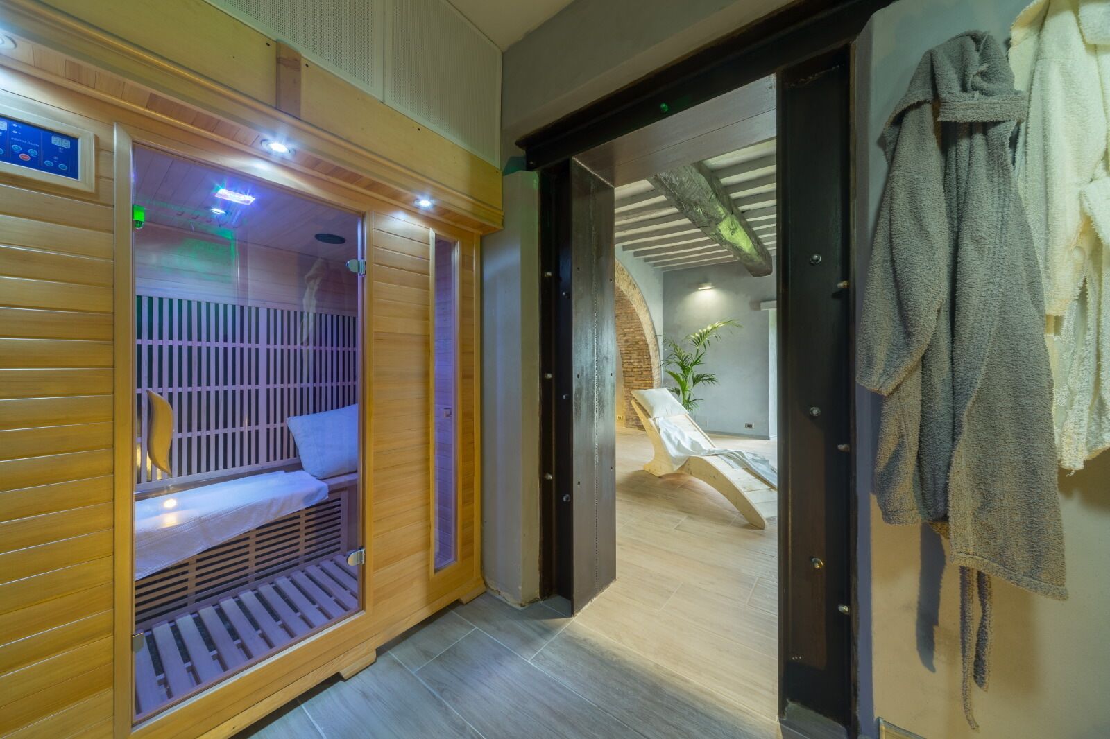 A sauna room with a wooden bench, a bench with a towel, and a towel rack.