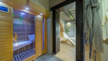 A sauna room with a wooden bench, a bench with a towel, and a towel rack.
