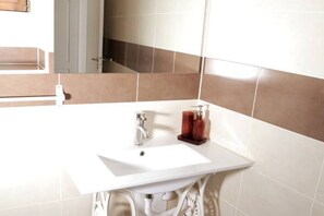 Une salle de bain avec un lavabo blanc, un miroir et un porte-serviettes.