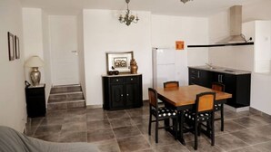 A compact kitchen with a dining table, chairs, a chandelier, and a refrigerator. - Casa Lourival (Penalva do Castelo)