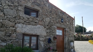 A stone building with a wooden door, a window, and a small balcony. - Casa Lourival (Penalva do Castelo)