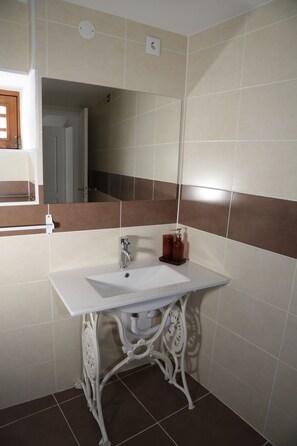 Une salle de bain avec un lavabo blanc, un miroir et des carreaux marron et blancs.