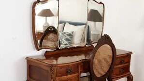 A wooden dresser with a mirror and a wicker chair. - Casa Lourival (Penalva do Castelo)