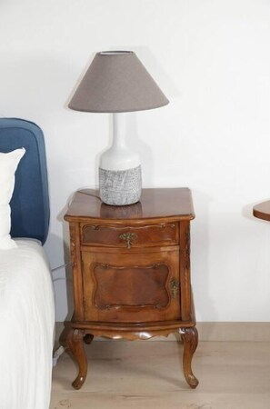 Une table de chevet en bois, avec une lampe et un vase décoratif.