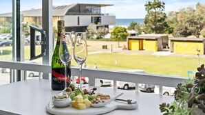 A balcony with a table set for a meal, a bottle of champagne, and two glasses. - Beachfront Bliss 2BR Broadbeach (Gold coast)