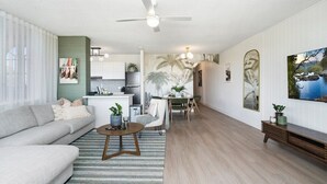 A modern living room with a sofa, coffee table, and dining area. - Beachfront Bliss 2BR Broadbeach (Gold coast)