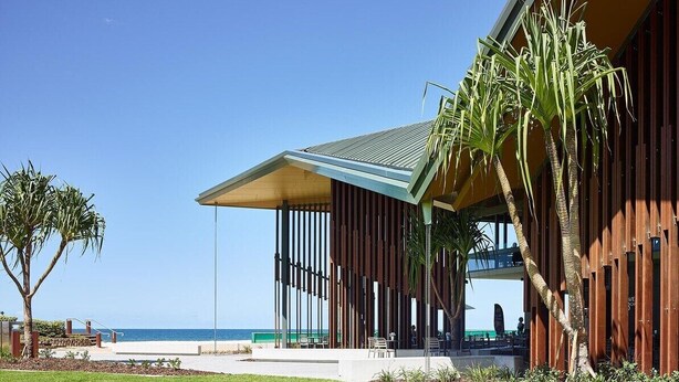A modern building with a sloped roof, large windows, and a view of the ocean. - Beachfront Bliss 2BR Broadbeach (Gold coast)