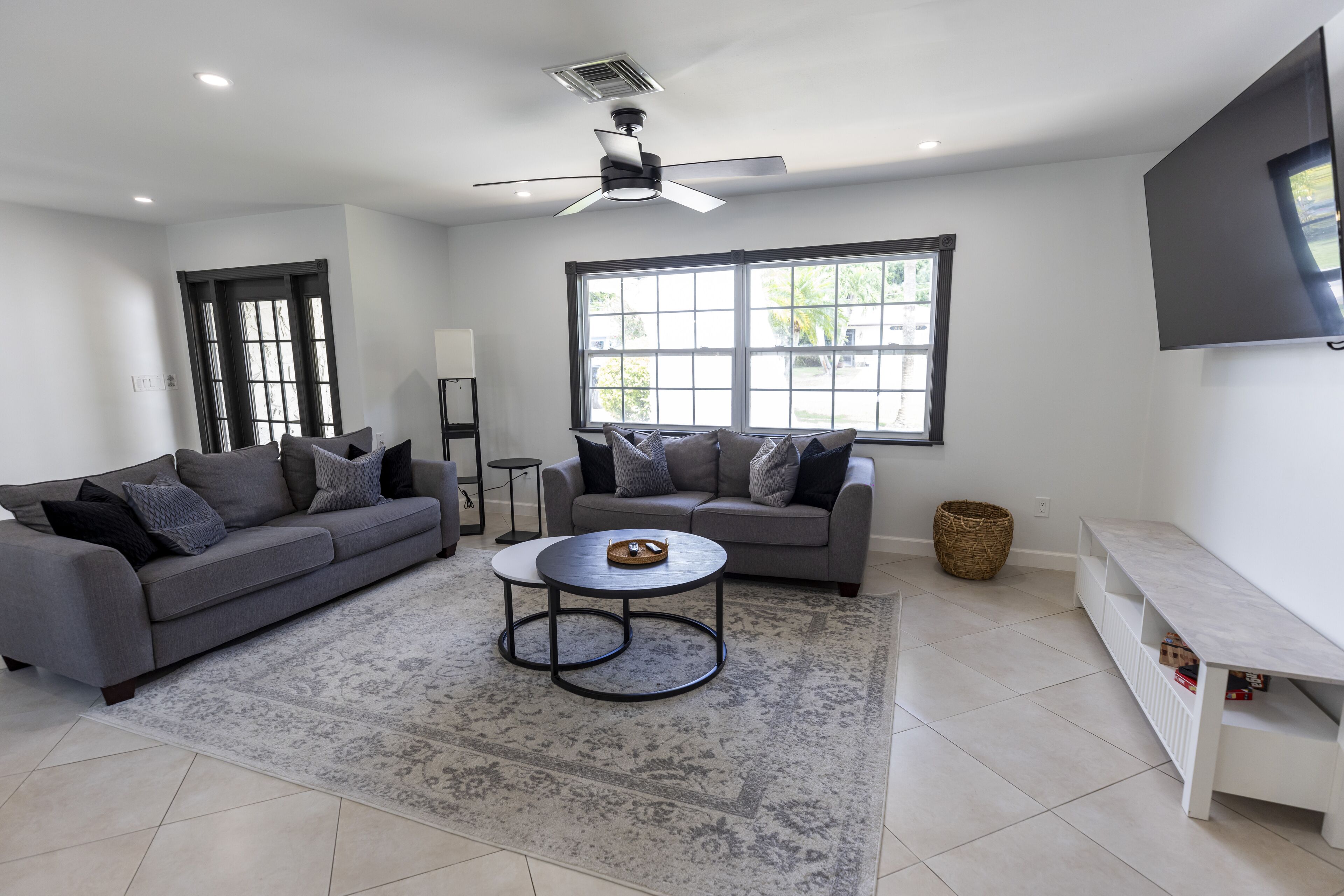 A modern living room with a grey sofa, a coffee table, and a large window.