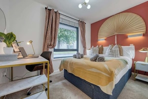 A bedroom with a bed, a desk with a laptop, a plant, and a window with curtains. - Stylish & Chic 1-BR Cosy Flat, City Centre Living (Southampton)