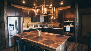 A modern kitchen with wooden cabinets, stainless steel appliances, and a central island with stools. - Experience the most stunning views the Ozarks have to offer (Jasper)