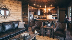 A cozy cabin interior with a wooden interior, a leather sofa, a dining table, and a chessboard. - Experience the most stunning views the Ozarks have to offer (Jasper)