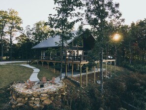 A cabin with a deck, stone fire pit, and outdoor seating.