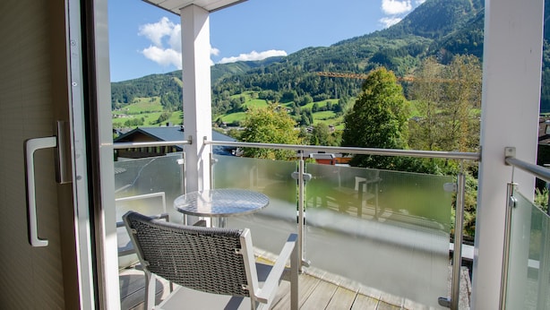 A balcony with a glass railing, a table, and a chair. - Apartment Glacier View 12.6. with balcony (Kaprun)