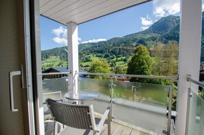 A balcony with a glass railing, a table, and a chair. - Apartment Glacier View 12.6. with balcony (Kaprun)