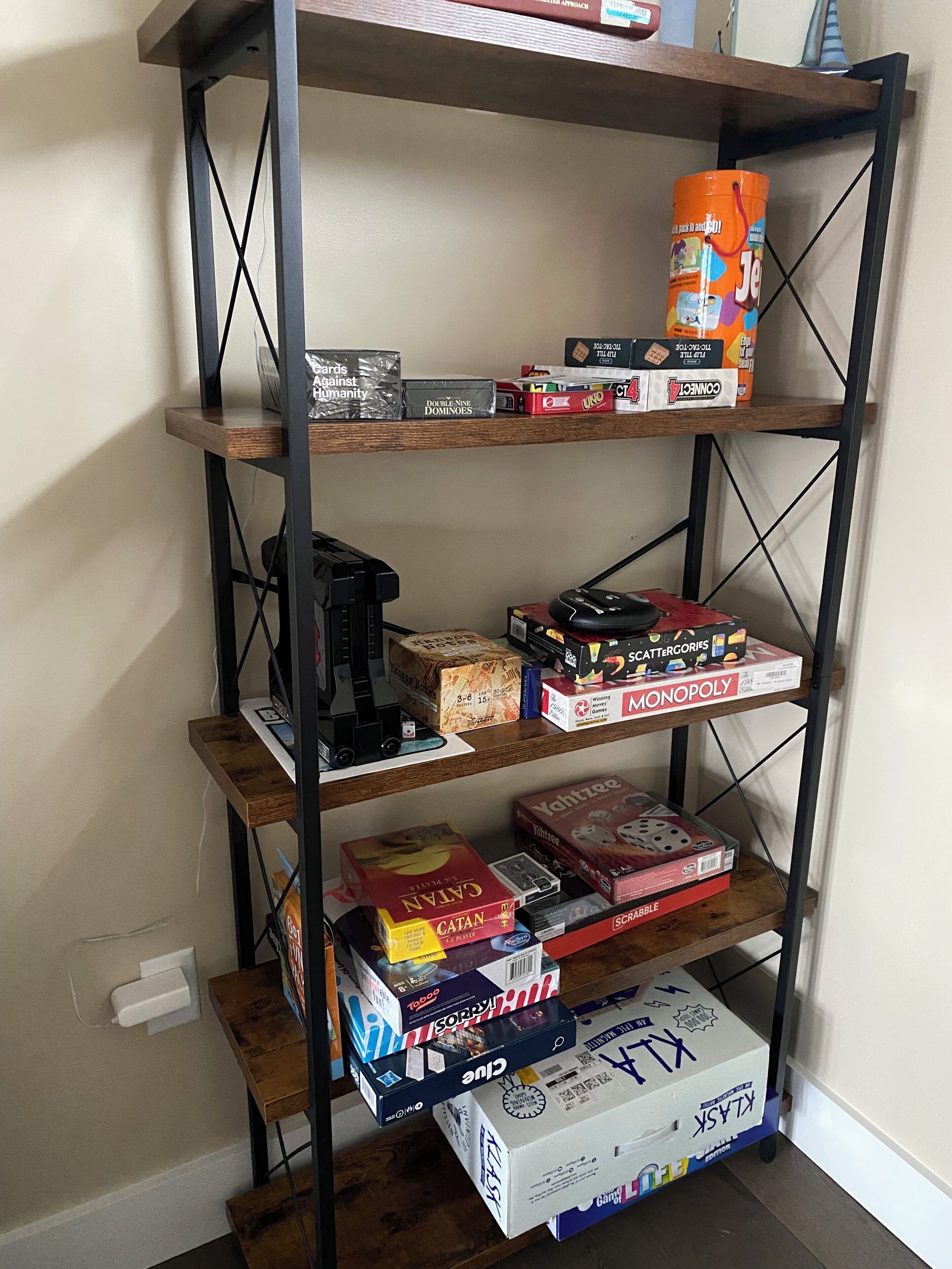 A metal shelving unit with various board games and a coffee machine.
