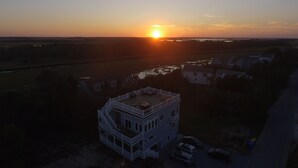 Eine Vogelperspektive zeigt ein zweistöckiges Gebäude mit Balkon, umgeben von Wasser und weiteren Gebäuden.