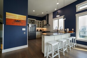 Una cocina moderna con armarios blancos, un refrigerador de acero inoxidable y una isla grande con taburetes de bar.