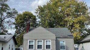 A single-story house with a grey exterior and a brick chimney.