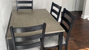 A dining table with four chairs, a white door, and a wooden floor.