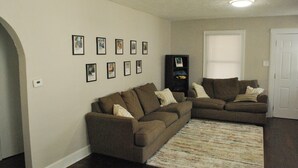 A living room with two couches, a rug, and framed pictures on the wall.