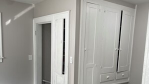 A hallway with a wooden floor, white doors, and a trash can.