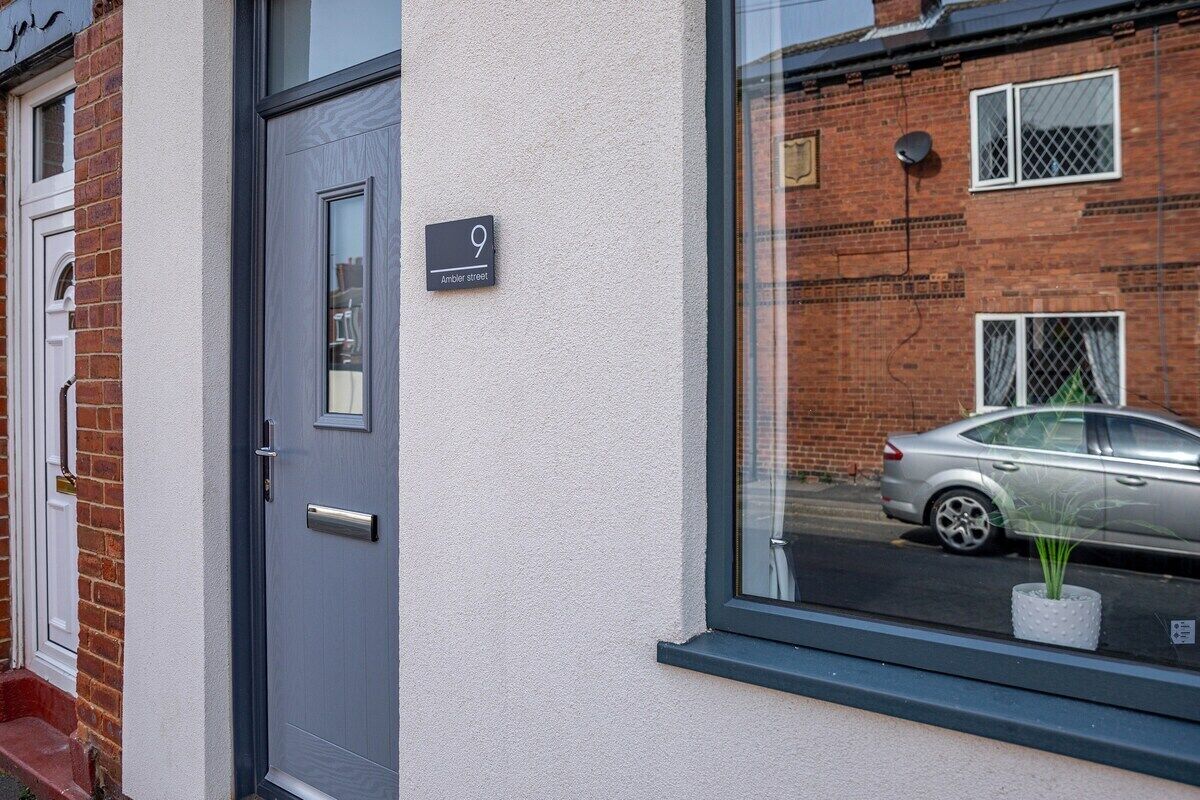 A modern building with a grey door and a window with a potted plant.