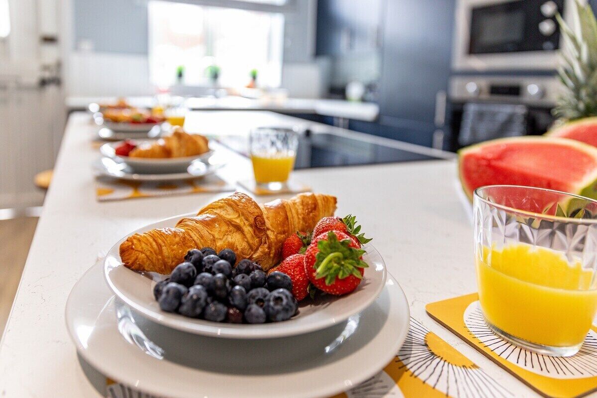 A breakfast setting with croissants, blueberries, strawberries, and a glass of orange juice on a table.