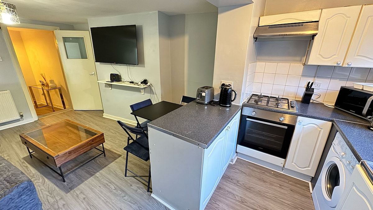 Een praktische keuken met een centraal eiland, een inbouwoven, een magnetron en een wasmachine.